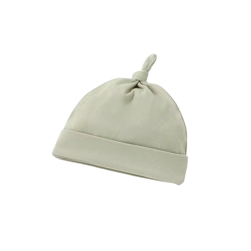 Light green baby hat with a knot on top against a white background