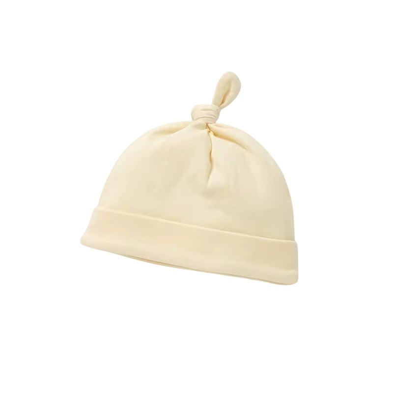 Beige baby hat with a knot on top against a white background
