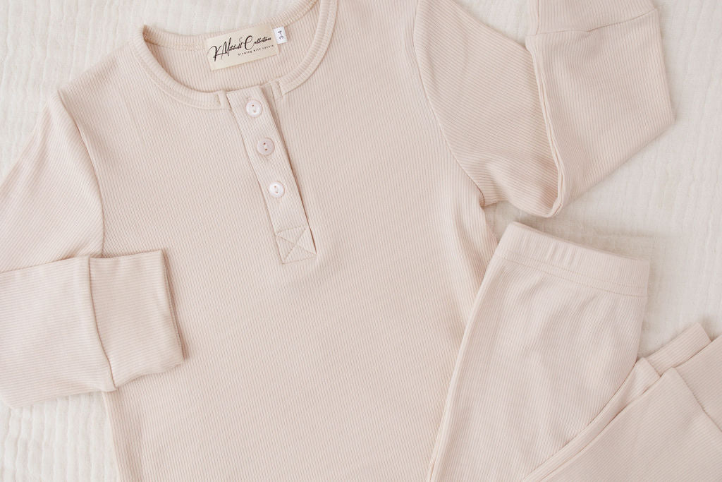 Beige long-sleeve shirt with buttons and matching pants on a white background