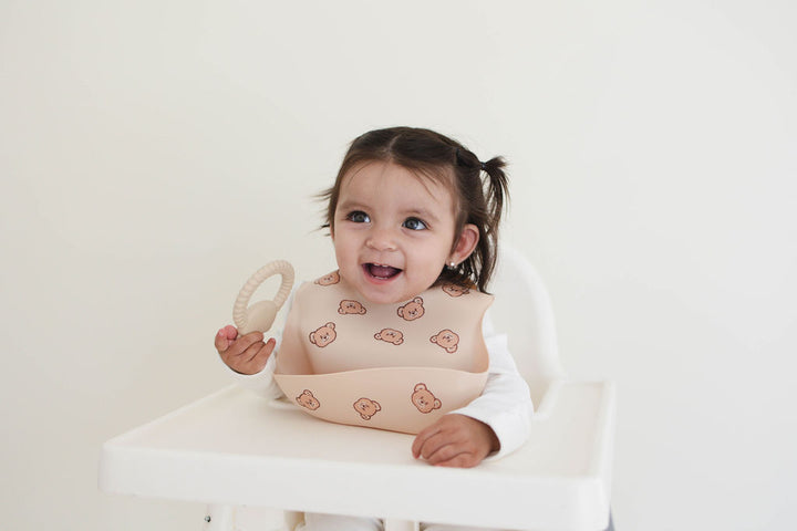 Child in a high chair wearing a bib with a white background