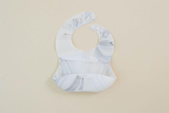 Baby bib with marble pattern on a beige background