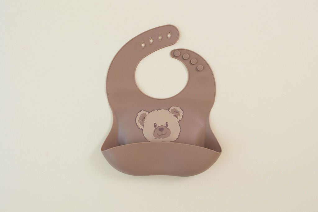 Brown bib with a teddy bear design on a beige background