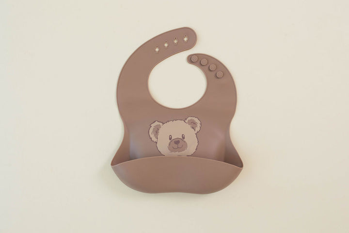 Brown bib with a teddy bear design on a beige background