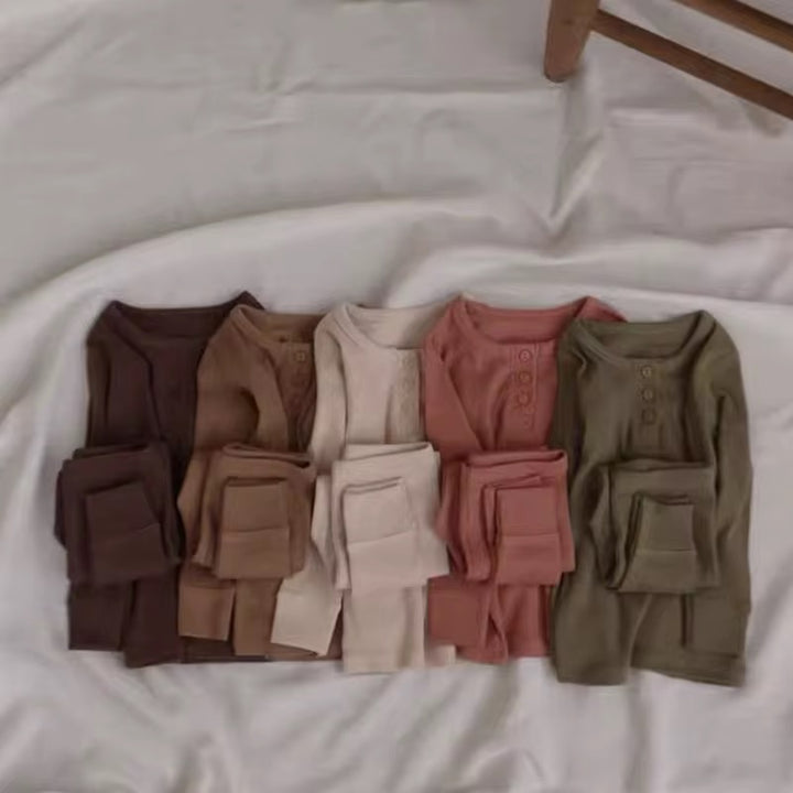Set of folded shirts in various earthy tones on a white surface